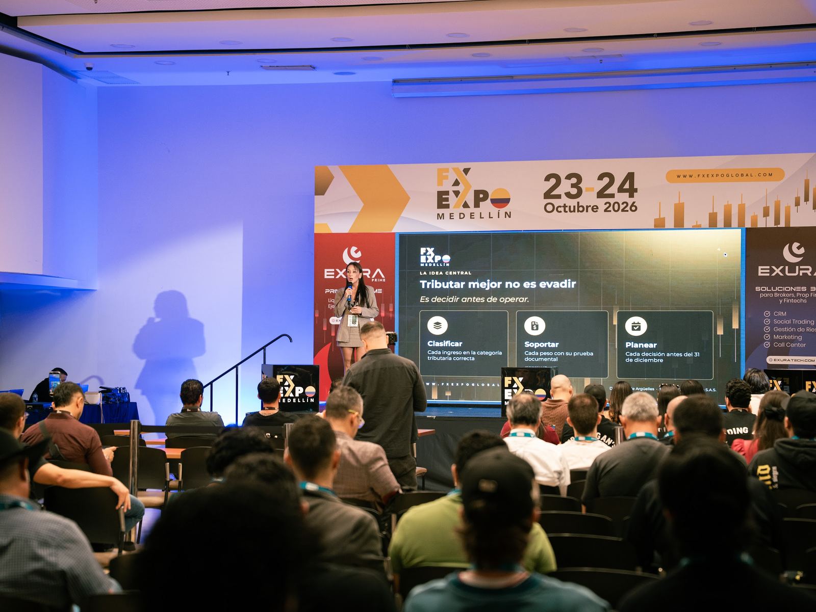 Speaker en el escenario principal ante una sala llena en FX Expo Medellín, octubre de 2026